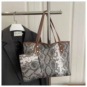 Vue détaillée du sac cabas imprimé serpent avec anses en cuir marron et rivets dorés