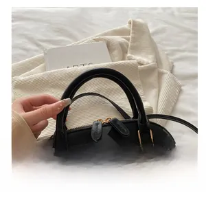 Detail of premium black leather shell bag with gold hardware and comfortable handle