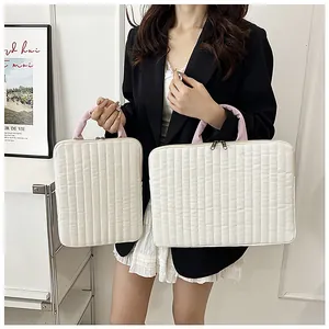 Detailed view of quilted laptop and tablet bags with pink handles in beige fabric