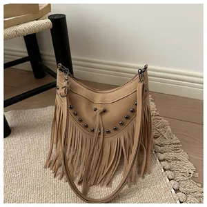 Close-up of bohemian khaki tassel bag with stud rivets on a textured indoor mat