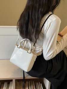 Minimalist white structured crossbody bag with gold hardware worn by a model