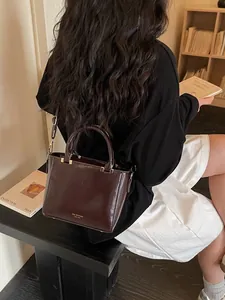 Classic dark brown glossy PU leather crossbody bag worn by a model in a cozy setting
