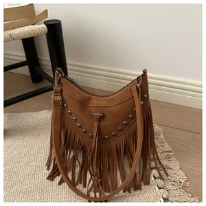 Close-up of brown suede hobo bag with vintage metal rivets and long bohemian fringe detail