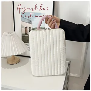 Close-up of white quilted laptop sleeve featuring pink pleated handles and silver zippers