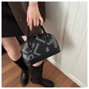 Detailed view of women's black shell bag with vintage geometric prints and gold hardware