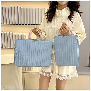Vertical and horizontal light blue quilted laptop sleeves with soft pink handles details