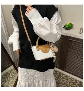 Detail of white lychee texture handbag with brown leather trim and cute bear charm
