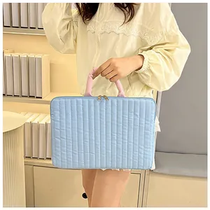 Macro shot of light blue quilted laptop sleeve with pink handles and zip details