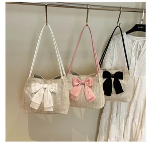 Detailed view of straw shoulder bags featuring white, pink, and black bow accents for summer
