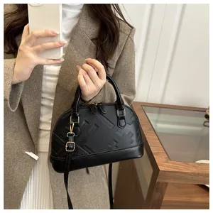 Detail of black shell crossbody bag with embossed texture shown on model side profile