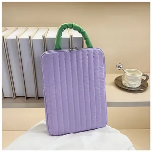 Detail of purple quilted laptop sleeve with green ruched handle and dual zipper closure