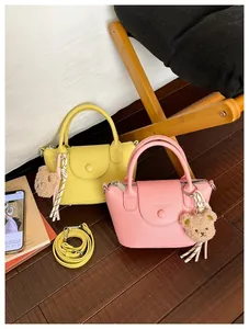 Detail of yellow and pink pebble leather handbags with plush bear charms and tassels