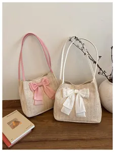Detailed view of handmade straw tote bag with large decorative pink bow on wooden table