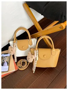 Detail of trendy tote bags in white and brown leather with cute bear charms and straps