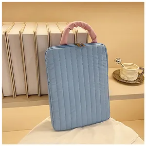 Detail of blue quilted laptop sleeve with pink pleated handles and gold metal zippers