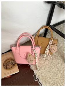 Detail of mini lychee texture leather handbags with plush bear charms and crossbody straps
