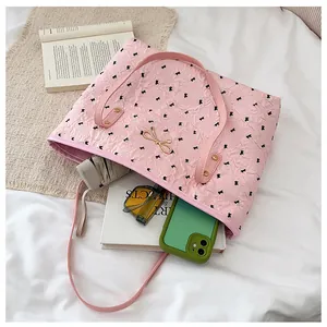 Détail d'un sac cabas rose avec motifs floraux, nœud métallique et intérieur spacieux