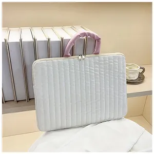 Detail of quilted laptop sleeve featuring pink pleated handles and dual metal zippers