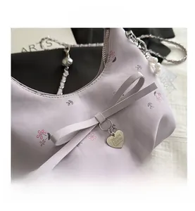 Détail du sac plissé lavande à fleurs avec nœud rose et breloque en métal en cœur
