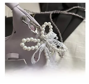 Détail du sac floral avec pendentif noeud perlé et rubans délicats en dentelle blanche