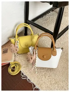 Close-up of textured mini handbags with bear pendant on a cozy beige plush rug
