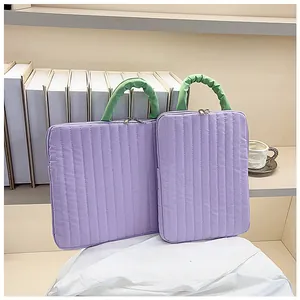 Detail of purple quilted laptop sleeve with green ruched handles and silver zippers