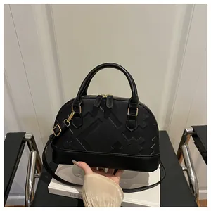 Close-up of black shell bag featuring textured geometric relief and gold hardware