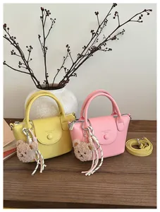 Detail of mini square leather handbags in yellow and pink with plush bear charms