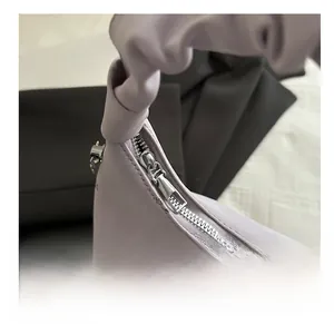 Gros plan du sac en cuir lilas avec poignée plissée et détail de fermeture éclair argentée