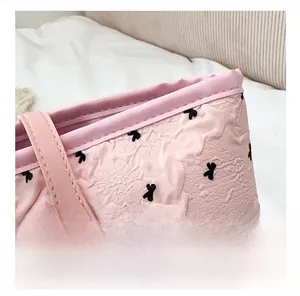 Vue détaillée du cabas rose avec motifs nœuds, texture plissée et rivet doré