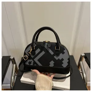 Close-up of black shell bag showing grey geometric pattern and gold hardware details