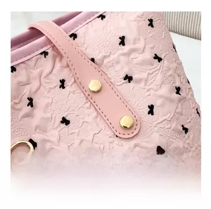 Détail du sac cabas rose avec motifs nœuds noirs et rivets métalliques dorés renforcés