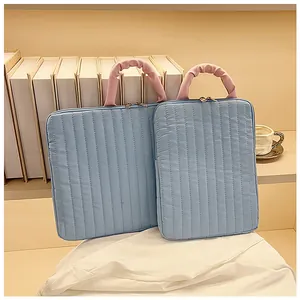 Detail of light blue quilted laptop sleeve with pink handles and dual metal zippers