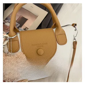 Detail of lychee pattern faux leather handbag with silver hardware and bear charm
