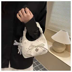 Détail du sac à main fleuri avec nœud décoratif et pendentif élégant en perles