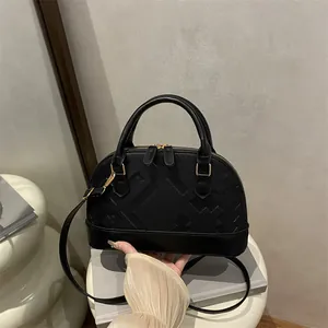 Minimalist black shell handbag with geometric texture and golden metal hardware