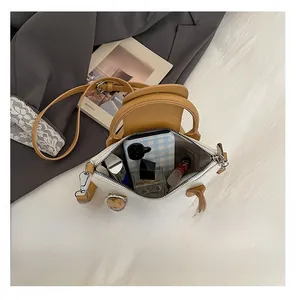 Top view of two-tone handbag interior showing phone, perfume, and lipstick capacity