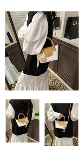 Detail of mini white lychee leather bag with brown handles and plush bear charm