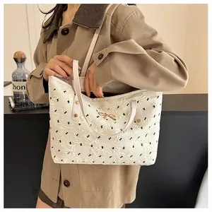 Détail d'un sac cabas crème avec motifs de nœuds noirs et garnitures dorées élégantes