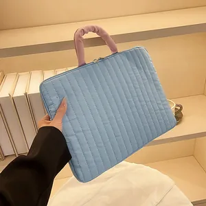 Sky blue quilted laptop sleeve with purple ruched handle in a cozy home office setting