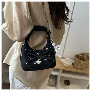 Détails de broderie florale et pendentif perle sur ce sac à main plissé noir