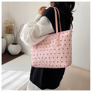 Détail du sac cabas rose montrant des motifs nœuds, texture plissée et breloque dorée