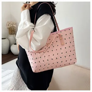 Détail d'un cabas rose avec imprimés nœuds noirs et petit nœud doré en métal