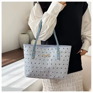 Détail du sac cabas plissé bleu clair avec nœuds noirs et emblème en métal doré