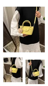 Detail of yellow lychee-grain PU leather handbag with cute plush bear charm