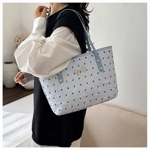 Détail d'un grand sac cabas bleu clair avec nœud doré et texture gaufrée élégante