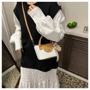 Close-up of mini two-tone leather handbag with plush bear charm and silk scarf detail