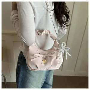 Détail d'un sac floral rose avec poignée plissée, nœud en perles et pendentif cœur doré