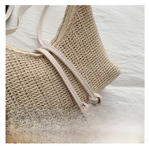 Dettaglio della borsa in paglia beige con trama intrecciata fine e tracolla con nodo