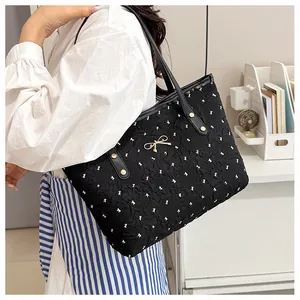 Vue détaillée du cabas noir avec motifs de nœuds blancs et petit nœud en métal doré chic